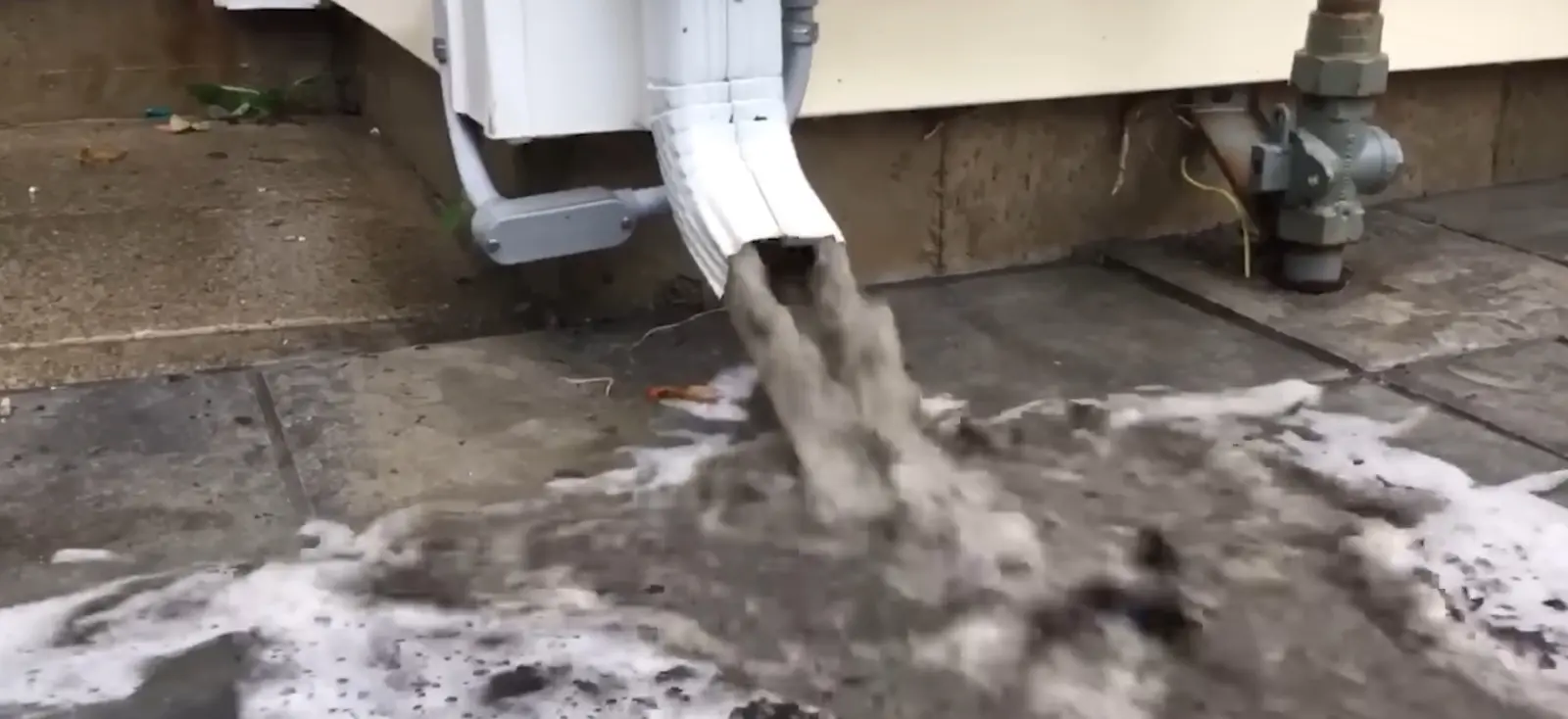 Downspout flushed clear during gutter cleaning for a Cheektowaga rental property